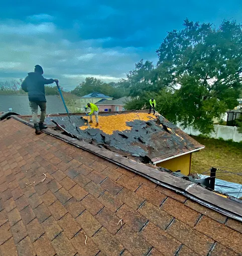 Roof tear-off on a waterfront home under a moody sky